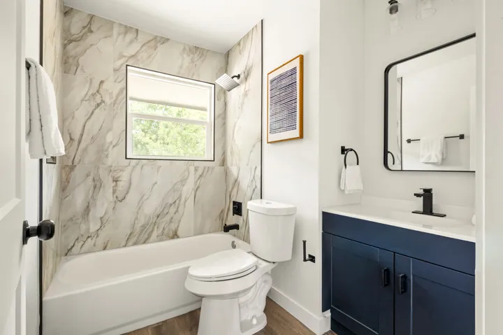 Bathroom with marble-look tile and navy vanity